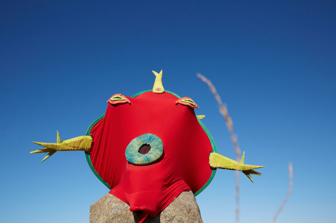 A person in a costume of a red mythical frog-like creature.